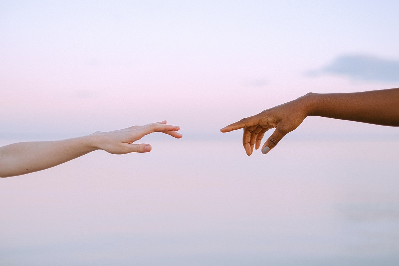 Two hands approaching to meet with a sky background