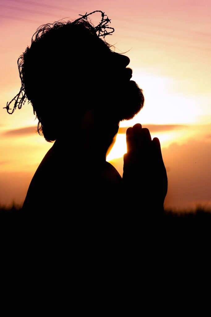 Secrets To Success  - An image showing the Sihoutte of a bearded male looking like a saint with wet hair praying in the background of a sunrise.