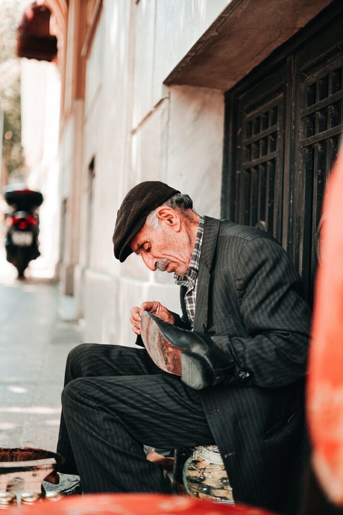 Do Startups Need Venture Capital? - A picture of an old man who seems to be working on a shoe by the roadside. The well-dressed old man seems to be a cobbler. 