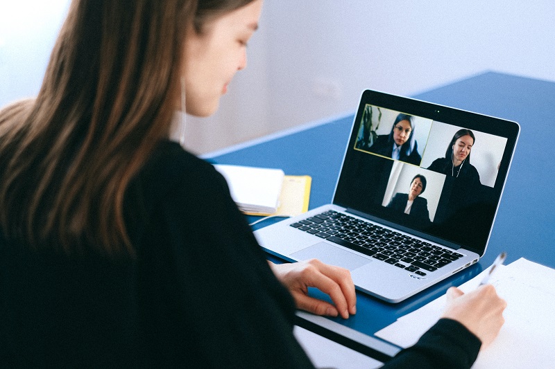 Is Higher Education A Scam? - A young woman learning while doing an online video conference with three other women in front of a laptop.