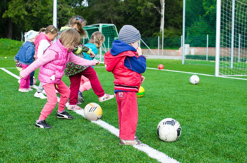 Children taking turns kicking footbal into the goal post