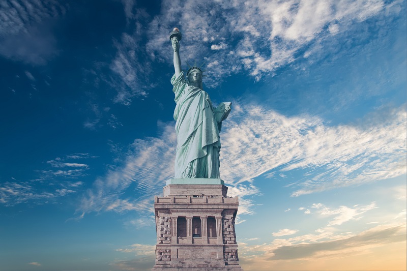 A shot of the statue of liberty with a few clouds around, presumably near sunset (unclear)