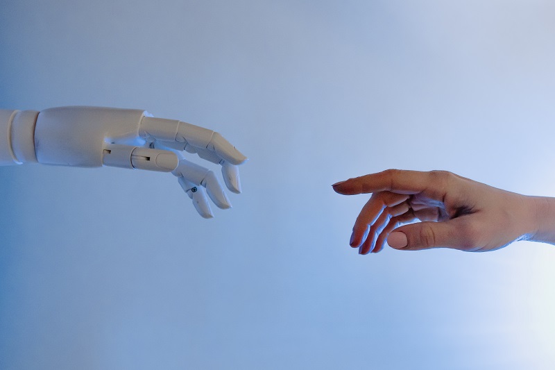 The hand of a human being and the hand of an artificial intelligence reaching out to touch each other