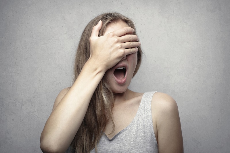 A woman closing her eyes with her hands in fear of cold water exposure