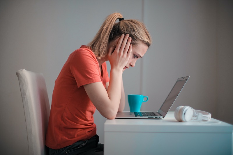 A woman worriedly looking at her laptop - an example of how you love negativity