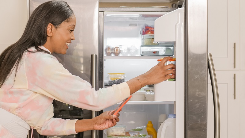 A woman picking up something from the fridge - to illustrate why you should cool down hot food before it goes in the fridge