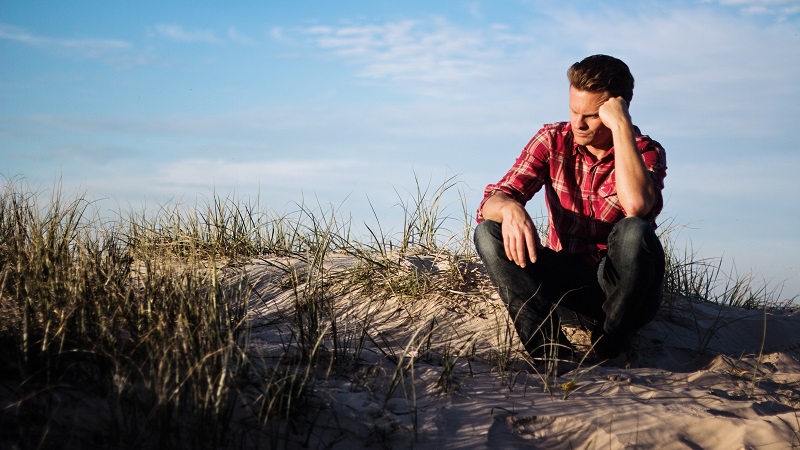 A man sitting on a beach pondering if there is any such thing as a stupid question.