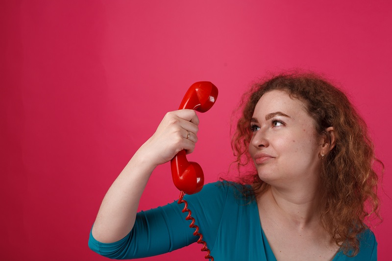 A picture of a person staring at an old phone, looking amusingly perplexed