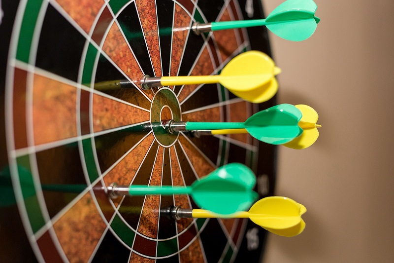 How to solve the dartboard paradox? - A picture of a dartboard with darts stuck on it.